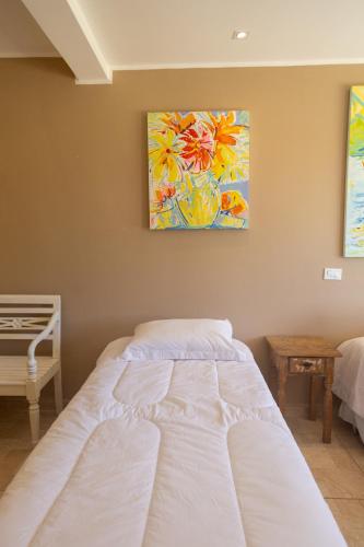 a white bed in a bedroom with a painting on the wall at Pousada La Dolce Vita in Búzios