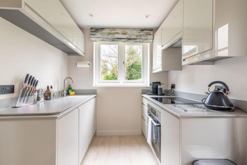 una cocina con armarios blancos y una ventana en Near Major Attractions Comfortable TV, en Bath