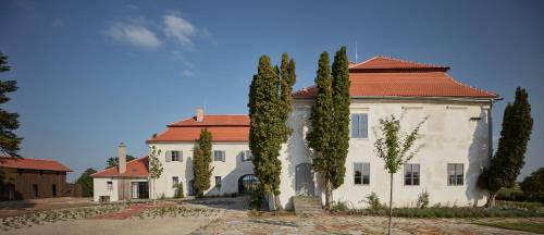a large white house with a red roof and trees at Kocanda Kravsko in Kravsko