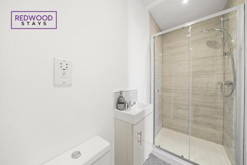 a white bathroom with a shower and a toilet at Quality 1 Bed 1 Bath Apartments For Contractors By REDWOOD STAYS in Farnborough