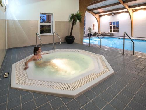 a woman in a hot tub next to a swimming pool at The Old Hall Hotel in Caister-on-Sea
