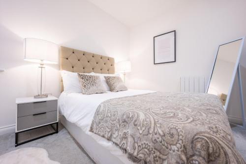 een witte slaapkamer met een groot bed en een lamp bij Free Parking | 2BR | WiFi in Cardiff