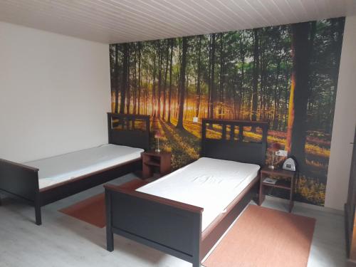 two beds in a room with a mural of a forest at Ferienwohnung im Theaterhof in Greußenheim