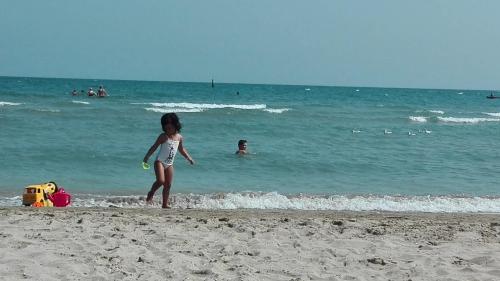a little girl standing on the beach with a frisbee at appartamento Colticciola Agriturismo Marche in Cagli