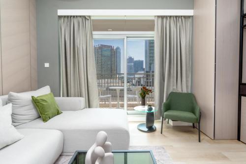 uma sala de estar com um sofá branco e uma cadeira verde em Downtown Dubai - CityApartmentStay em Dubai