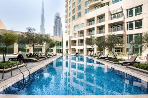 uma grande piscina com cadeiras e um edifício em Downtown Dubai - CityApartmentStay em Dubai