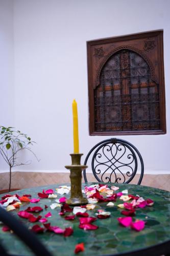 a table with a candle and pink flowers on it at RIAD LAICHI in Marrakech