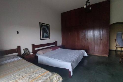 a bedroom with two beds and a chair at Casa de campo Sede de Fazenda - MT in Nossa Senhora do Livramento