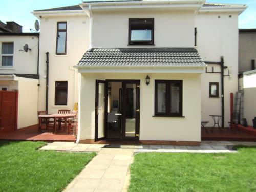una casa bianca con una porta nera e un patio di Aberdeen Guest House a Ilford