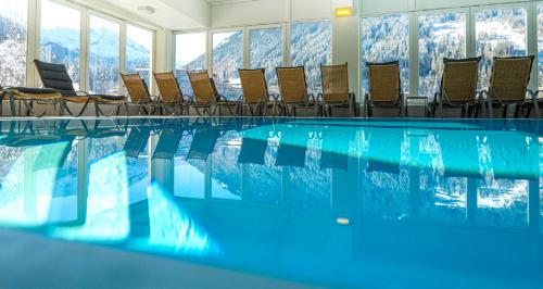 uma piscina com cadeiras e montanhas ao fundo em Panorama Spa Lodges DAS.SCHILLER em Bad Gastein