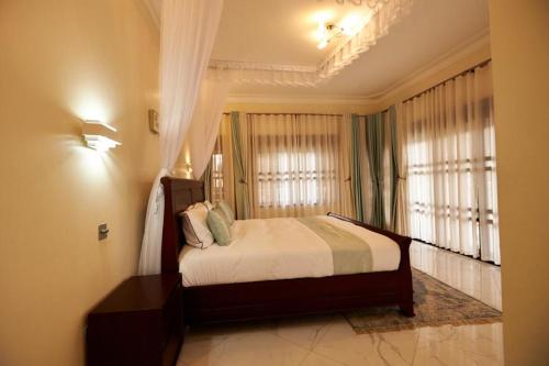 1 dormitorio con 1 cama en una habitación con ventanas en The Forest House - Kawuku-Bunga en Kampala