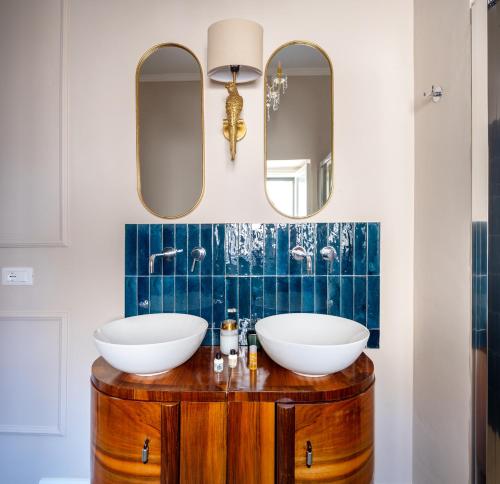 a bathroom with two sinks on a wooden vanity with mirrors at Ziolì in Noto