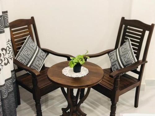 twee stoelen en een tafel met een plant erop bij IBEEZA MOTEL in Babarenda Central