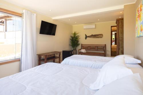 a bedroom with two beds and a tv on the wall at Pousada La Dolce Vita in Búzios
