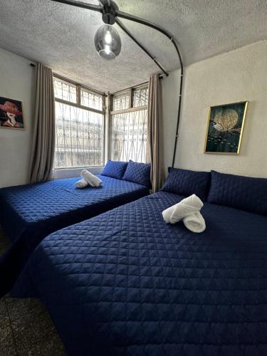 2 Betten in einem Schlafzimmer mit blauer Bettwäsche in der Unterkunft CASA MAGNOLIA in Guatemala