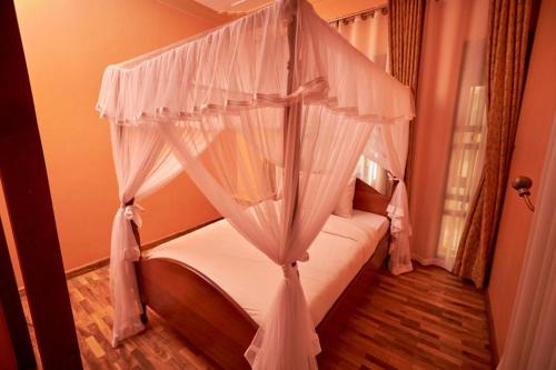 a bedroom with a canopy bed with white curtains at The Forest House - Kawuku-Bunga in Kampala