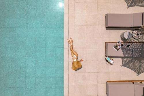 une personne se posant à l'étage à côté d'une piscine dans l'établissement OPSIS Suites, à Limenaria