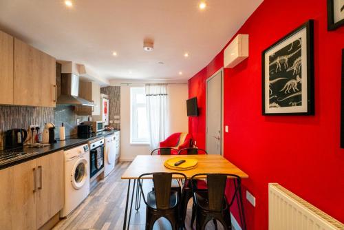 een keuken met rode muren en een tafel en stoelen bij Cardiff Getaway - City Center - Free Parking in Cardiff