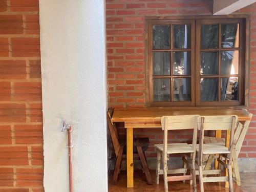 een houten tafel met 2 stoelen en een raam bij Rosas287 in Puerto Iguazú