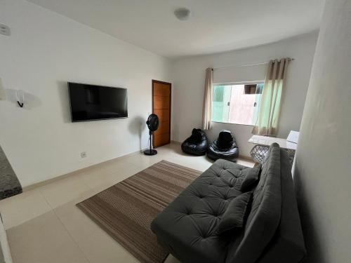 a living room with a couch and a flat screen tv at Apartamento Aconchegante in Capitólio