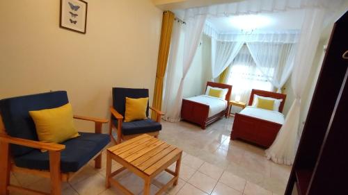 a room with two beds and a table and chairs at The Forest House - Kawuku-Bunga in Kampala