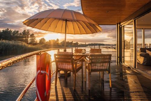 einen Tisch mit Stühlen und einen Regenschirm auf einem Boot in der Unterkunft Hausboot Möwe 2 - LP2 in Laasow