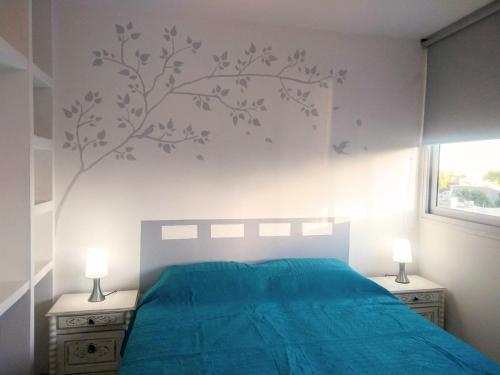 1 dormitorio con 1 cama azul y un mural en la pared en COZY II DEPARTAMENTO EN PLENO CENTRO DE MENDOZA en Mendoza