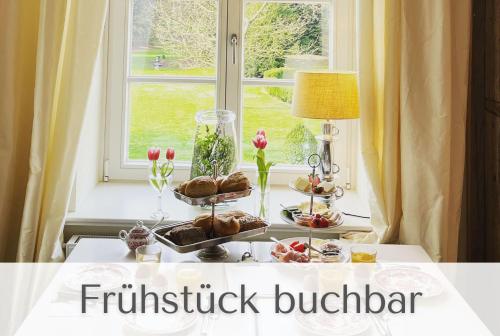 uma mesa com comida e flores numa janela em Gutshaus Volzrade em Volzrade