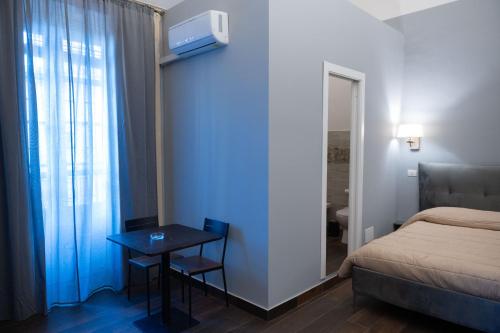 1 dormitorio con cama, mesa y ventana en B&B Palazzo Fischetti en Catania