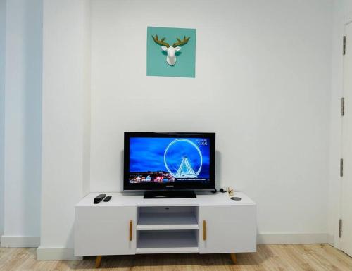 een flatscreen-tv zittend op een wit entertainment center bij Nórdico -Apartamentos Birdie- in Albacete