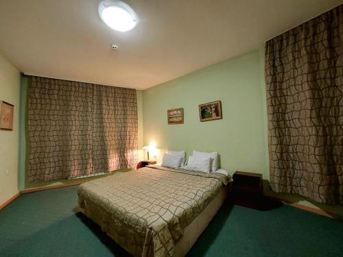 a bedroom with a bed and a window with curtains at Family Art Hotel Gallery in Pleven