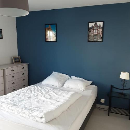 - une chambre dotée d'un mur bleu et d'un lit avec des oreillers dans l'établissement Maison avec jardin à Mers les Bains, à Mers-les-Bains
