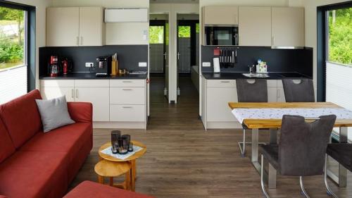 a kitchen and living room with a red couch and a table at Hausboot Möwenschiss - LP3 in Höxter