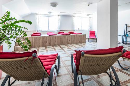 uma sala de espera com almofadas vermelhas nas cadeiras em Panorama Spa Lodges DAS.SCHILLER em Bad Gastein