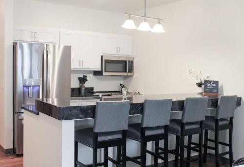 a kitchen with a bar with chairs and a refrigerator at Main Street Sun Prairie WI - 2 Bedroom in Sun Prairie