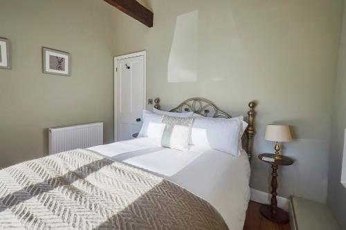 una camera da letto con un grande letto bianco con cuscini bianchi di Host & Stay - Snoozy Goose a Ovingham