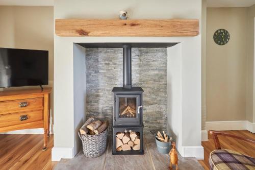 a fireplace in a living room with a wood stove at Host & Stay - Snoozy Goose in Ovingham