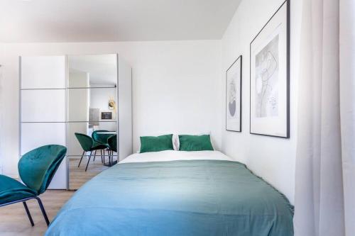 - une chambre avec un lit et deux chaises vertes dans l'établissement La Suite : studio Hypercentre - Cathédral, à Amiens