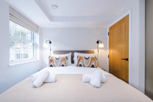 a white bedroom with a large bed with two pillows at Rock Mill - Deluxe Studio Apartments in Stoney Middleton