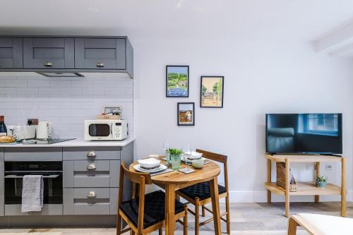 a kitchen with a small table in a kitchen with a tv at Rock Mill - Deluxe Studio Apartments in Stoney Middleton