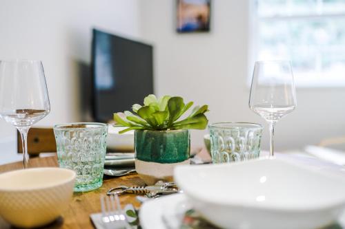a table with wine glasses and a plant on it at Rock Mill - Deluxe Studio Apartments in Stoney Middleton