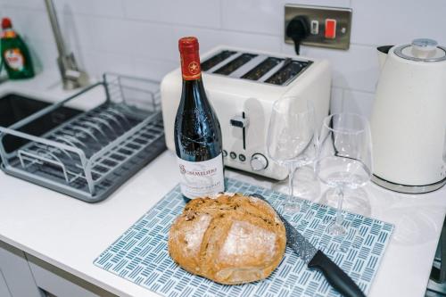 a bottle of wine and a loaf of bread on a counter at Rock Mill - Deluxe Studio Apartments in Stoney Middleton