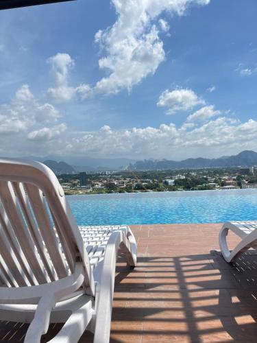 two white chairs sitting on a deck next to a pool at The Horizon Ipoh By Iconique Espace in Ipoh