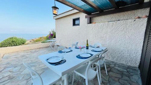 - une table blanche avec des chaises et une bouteille de vin dans l'établissement Appartement Solane 2 LUMIO, à Lumio