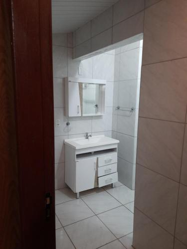 uma casa de banho branca com um lavatório e um espelho em Pousada dos Nonni em Garopaba