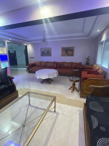 ein Wohnzimmer mit einem Sofa und einem Tisch in der Unterkunft Appartement spacieux à seulement 10minutes de la plage d'Agadir in Agadir