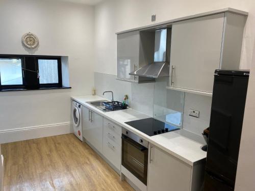 eine Küche mit weißen Schränken und einem schwarzen Kühlschrank in der Unterkunft No 10, St James Street, Burnley in Burnley