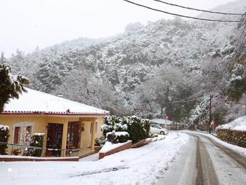 a snow covered street with a house and a mountain at Archontiko tou Ziaka in Ipáti