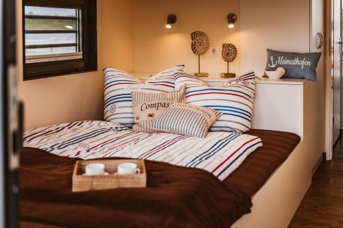 Cama en habitación pequeña con almohadas a rayas en Hausboot Hering - LP7, en Höxter