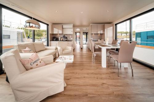a living room with white furniture and a dining room at Hausboot Hering - LP7 in Höxter